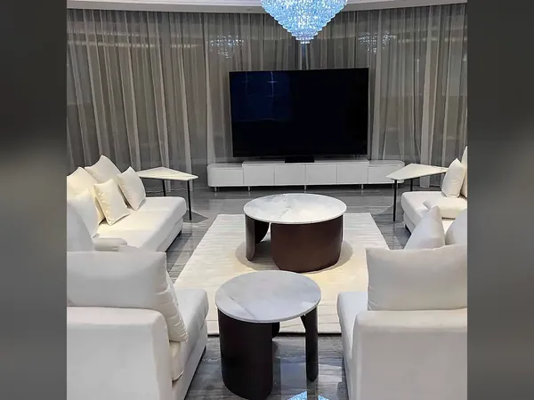 Living room with a television wall, cream sofas and marble tables
