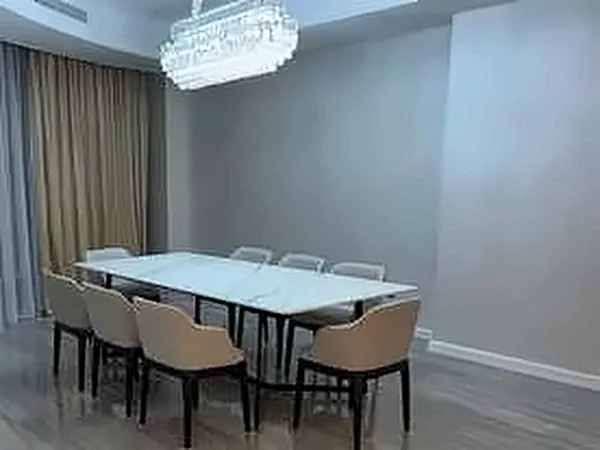 Dining room with a glass-top table, upholstered chairs and a chandelier
