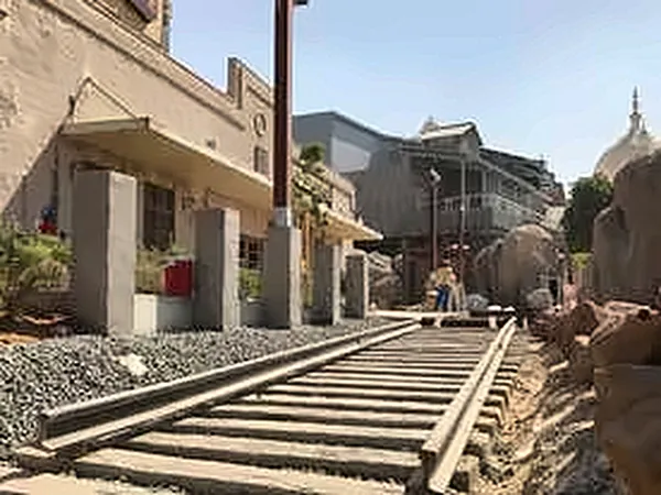 Track curving past stone-clad themed buildings