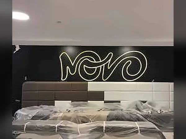 Novo logo in illuminated lettering above a padded wall during installation